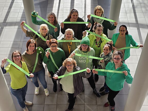 Eine Gruppe Mitarbeiter hält Bänder mit der Aufschrift "Tag der Kinderhospizarbeit" hoch