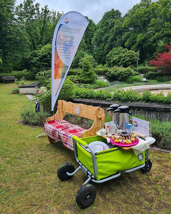 Mobiles Trauercafe: Eine Bank und ein Bollerwagen mit Kaffee und Kuchen